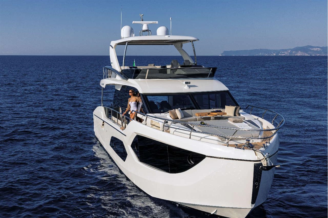 Luxury yacht sailing on deep blue waters, featuring a woman in a white swimsuit relaxing on the deck with sun loungers.